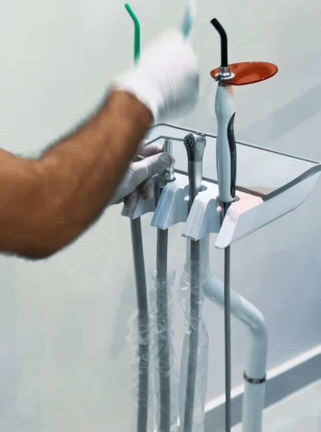 Gloved hand preparing instruments at the dental unit